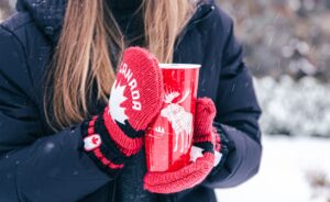 caneca e luva do canadá na neve na mão de uma mulher