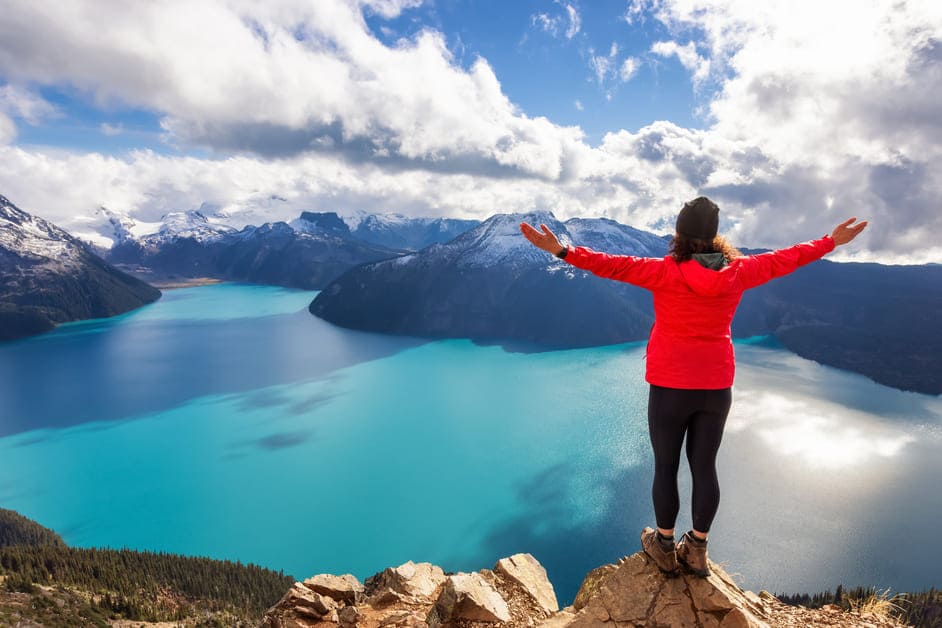 Mulher de pé em penhasco olhando para o lago no Canadá