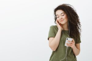 mulher com fone de ouvido camisa verde e celular na mao
