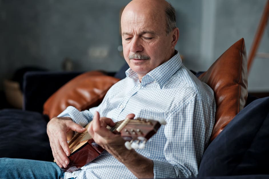 senhor em casa tocando seu violão