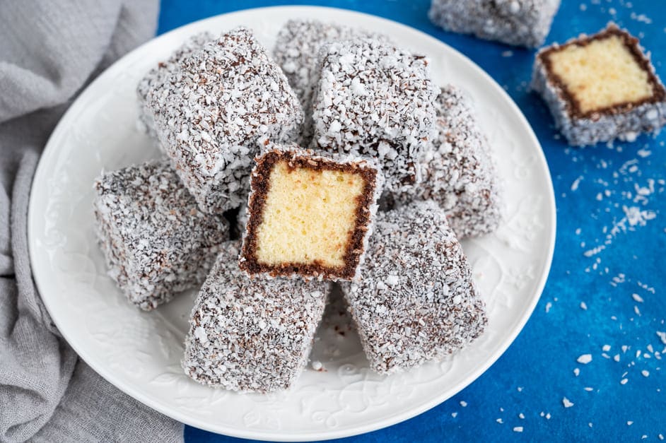 Traditional Australian Lamington cake in chocolate glaze and coconut flakes on a white plate