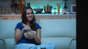 mulher assistindo filme no sofá comendo pipoca