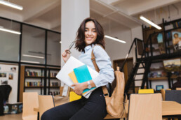 menina levantando e sorrindo com livro na mao