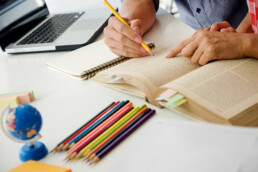 livro com lapis coloridos na frente e pessoa estudando