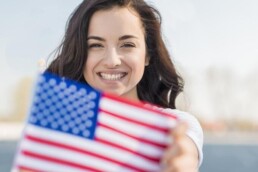 mulher sorrindo segurando bandeira dos estados unidos