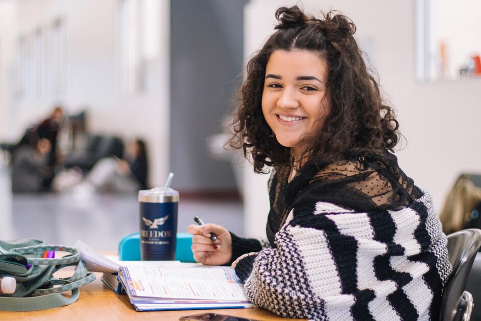 Estudante sorrindo com materiais escolares