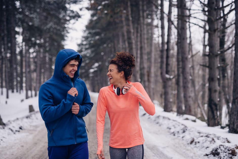 Amigos caminhando com blusas de frio em uma rua com neve