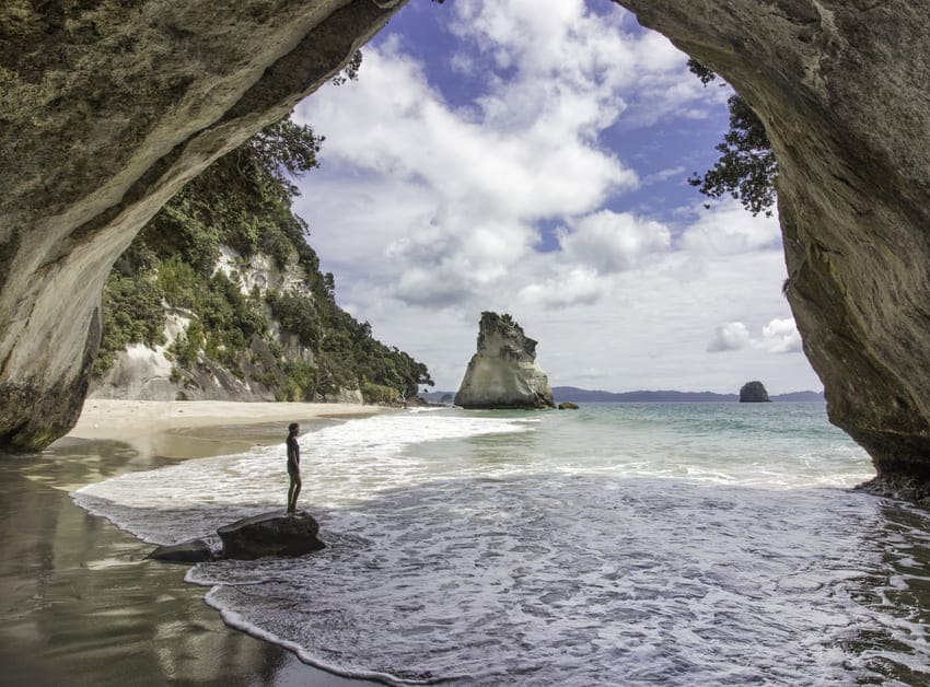 homem dentro de Cathedral Cove na Nova Zelândia