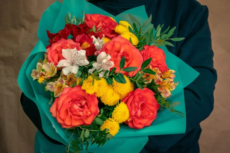 Pessoa segurando buque de flores vermelhas e amarelas