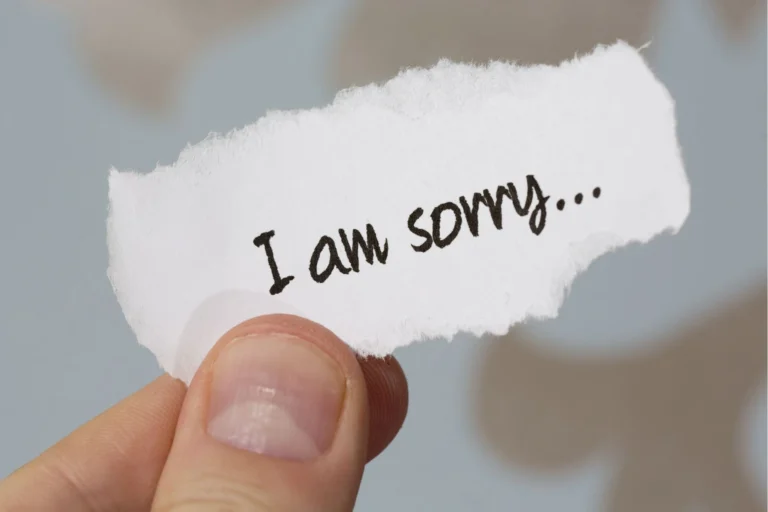 Mão segurando pedaço de papel escrito "i am sorry"